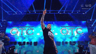 a man is standing on a stage in front of a large screen with the word otc on it .