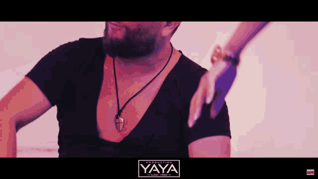 a man wearing a black shirt and a necklace with the word yaya on the bottom