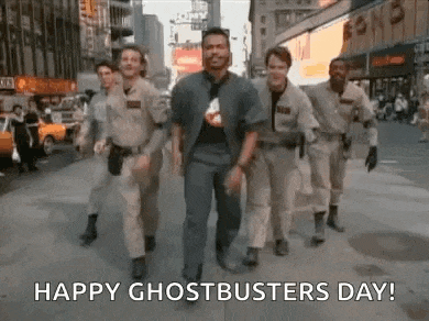 a group of men in ghostbusters costumes are walking down a street .