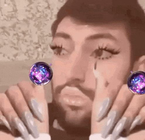 a man with a beard and long nails is wearing a pair of earrings .