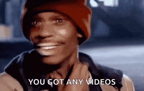 a man wearing a beanie is smiling and says you got any videos .