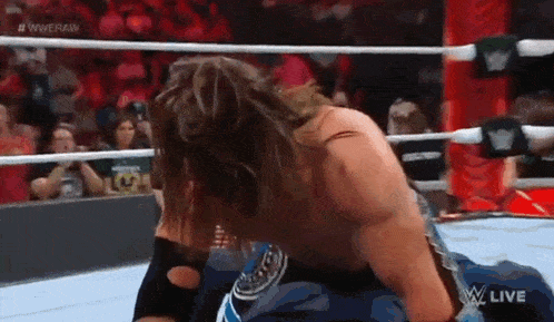 a wrestler is kneeling down in a wrestling ring with his head down .