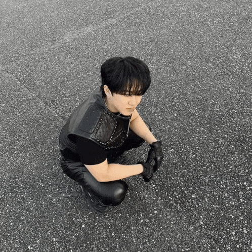 a man in a black leather vest is kneeling down