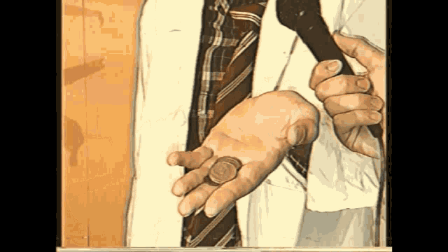 a man in a plaid tie is holding a penny in his hand