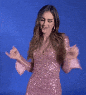 a woman in a pink dress is dancing with her arms outstretched against a blue background .