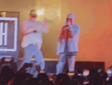 a man in a hoodie is singing into a microphone
