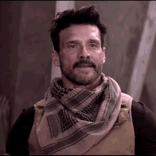 a man wearing a scarf around his neck looks at the camera