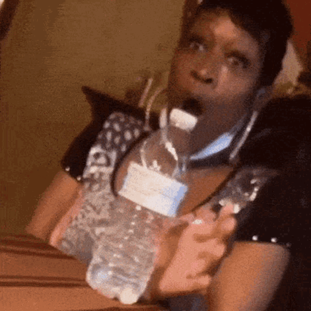 a woman is holding a water bottle in her mouth