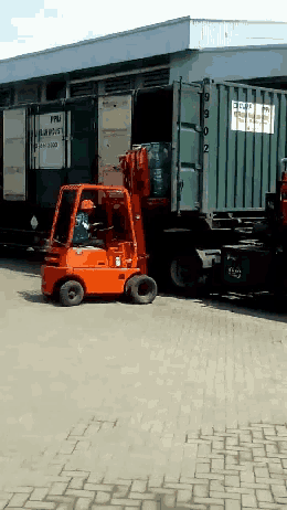 an orange forklift is parked in front of a container that says fmu on it