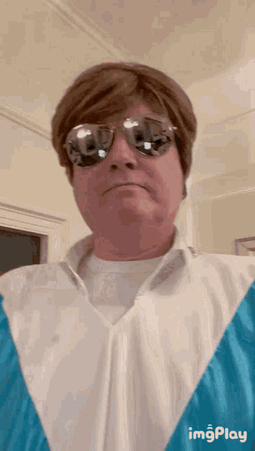 a man wearing sunglasses and a white shirt with a blue jacket