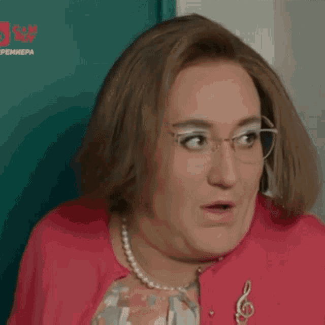 a woman with glasses and a pearl necklace is wearing a pink jacket