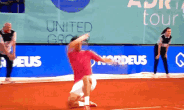 a man in a red shirt is playing tennis in front of a banner that says united group