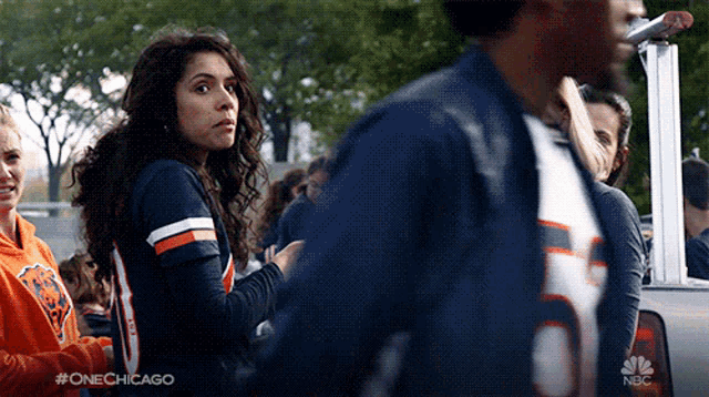 a woman wearing a chicago bears jersey stands in a crowd of people