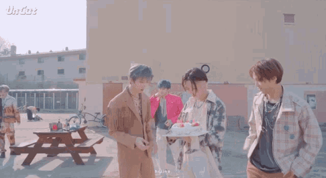 a group of young men are standing next to each other holding a cake .