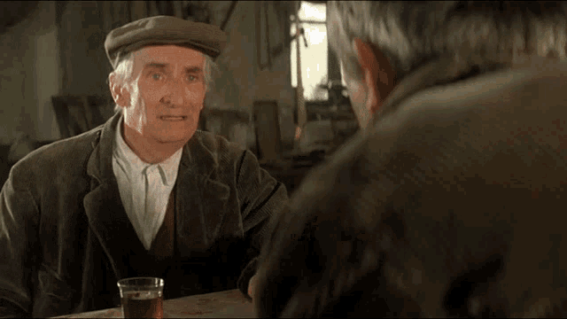 a man sitting at a table with a glass of beer and a sign that says " ah ! "
