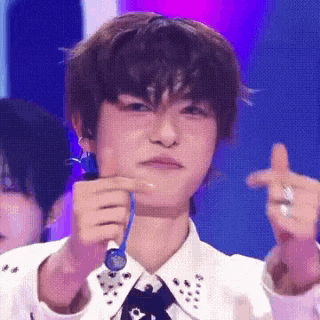 a young man is holding a microphone in his hand and making a funny face on a stage .