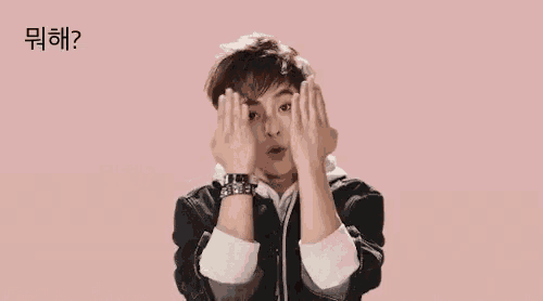 a young man with his eyes closed is making a funny face with his hands in the air .
