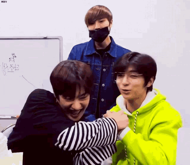 a man in a neon yellow hoodie is hugging another man in a black and white striped shirt