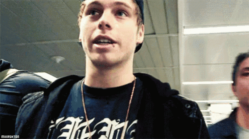 a young man wearing a black t-shirt that says ' arcane ' on it is looking at the camera .
