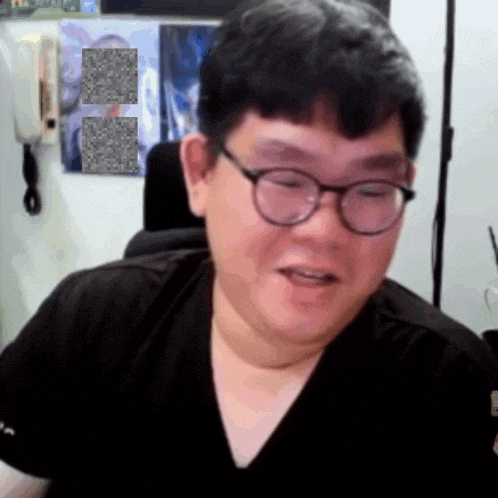 a man wearing glasses and a black shirt is sitting in a chair
