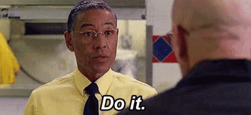 a man in a yellow shirt and tie is talking to another man in a kitchen and saying `` do it '' .