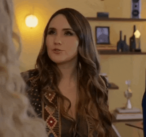 a woman with long hair is standing next to another woman in a living room .