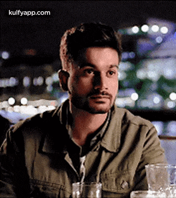 a man with a beard is sitting at a table with glasses .