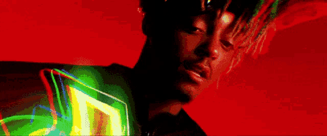 a close up of a man 's face with a red background and a green light behind him .