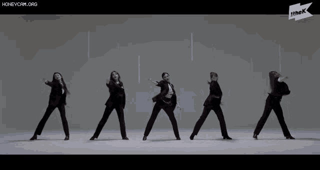 a group of women in suits are dancing in front of a sign that says honeycam.org