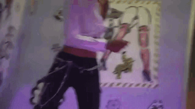 a woman is standing in front of a purple wall with a picture of a woman on it