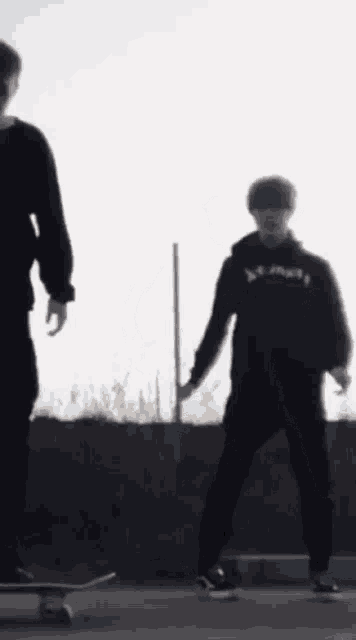 a person wearing a thrasher hoodie is standing next to a person on a skateboard