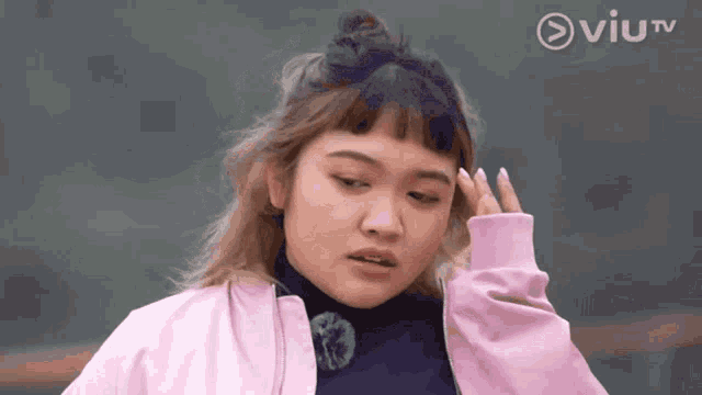 a woman in a pink jacket is standing in front of a tv screen that says viutv