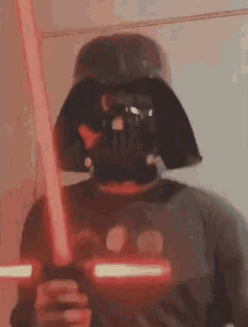 a man is wearing a darth vader mask and holding a lightsaber .