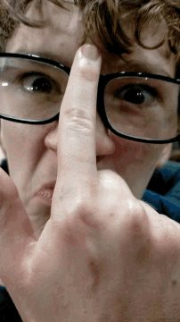 a close up of a person 's face with glasses and a finger on their nose