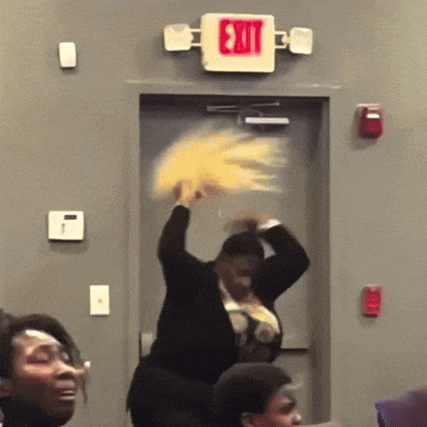 a woman is holding a fan in front of a red exit sign