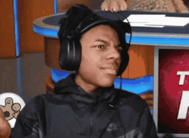 a young man wearing headphones in front of a tv screen with the letter t on it