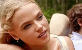 a close up of a woman 's face with a man behind her