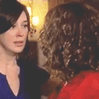 a woman in a blue shirt is talking to another woman with curly hair .