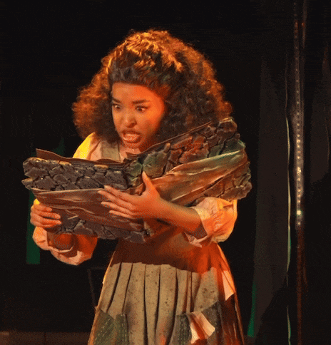 a woman with curly hair is holding a large piece of wood in her hands