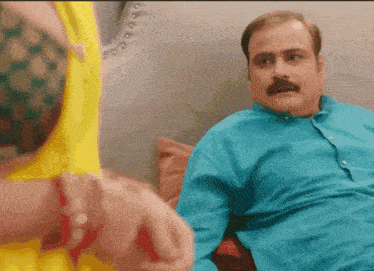 a man with a mustache is sitting on a couch