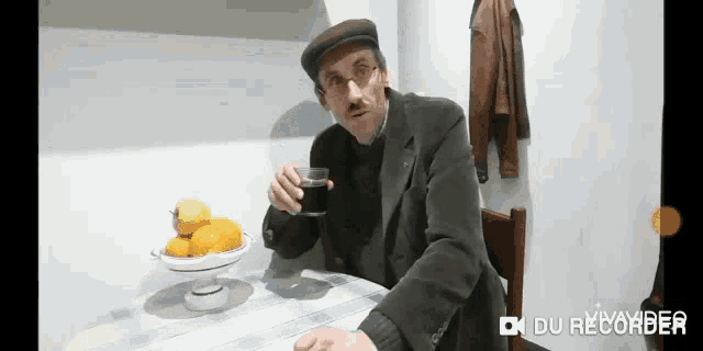 a man is sitting at a table with a glass of water and a bowl of lemons ..