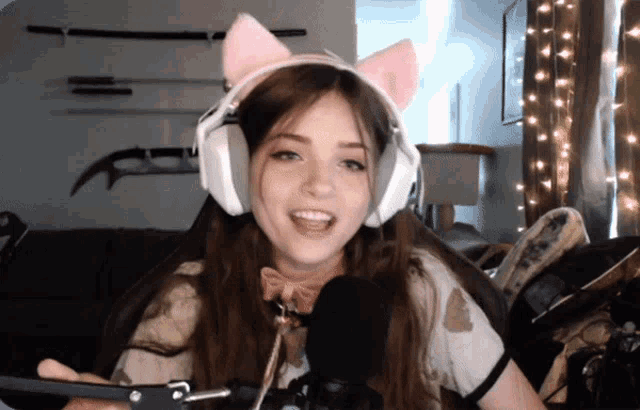 a girl wearing a pink cat ear headset is smiling