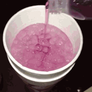 a purple liquid is being poured into a cup of ice .