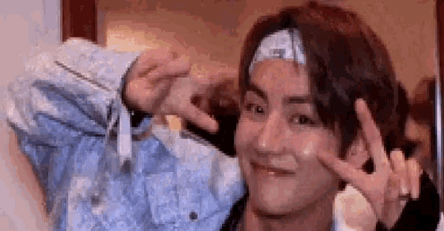 a man wearing a headband is making a peace sign with his hands .