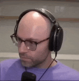 a bald man wearing glasses and headphones .