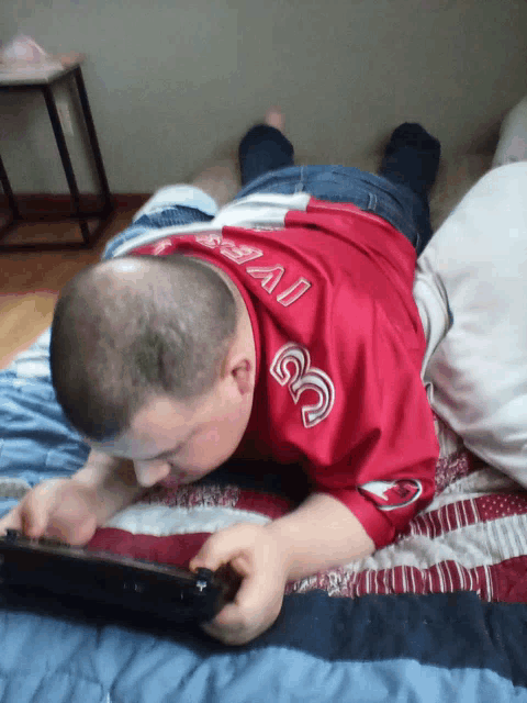 a man laying on a bed wearing a red shirt with the number 33 on the back