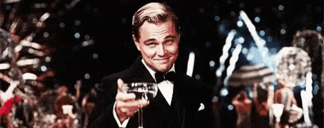 a man in a tuxedo is holding a glass of wine in his hand .