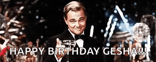 a man in a tuxedo is holding a glass of champagne and says happy birthday gesha
