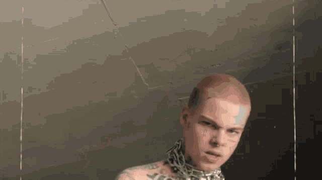 a man with a chain around his neck and a tattoo on his face .