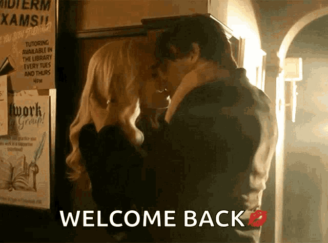 a man and woman are kissing in front of a sign that says welcome back